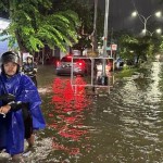 Seorang pengendara motor sedang mendorong motornya di tengah genangan air.-1710384732